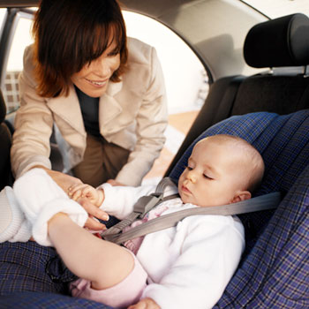 Photo of a working mother buckling her baby in the infant car seat